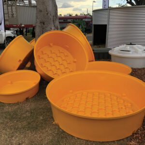 Pile of Nu-Tank's bright yellow molasses troughs at field day. Showing patented safety tread floor.