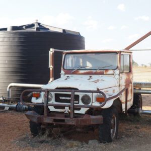 Nu-Tank Round Molasses Storage Tank, beside old rusty ute.